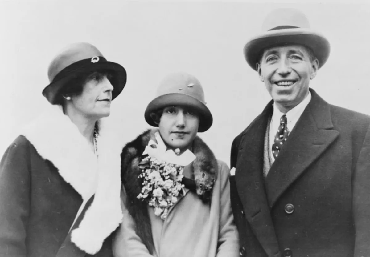 Three light-skinned people in brimmed hats and coats