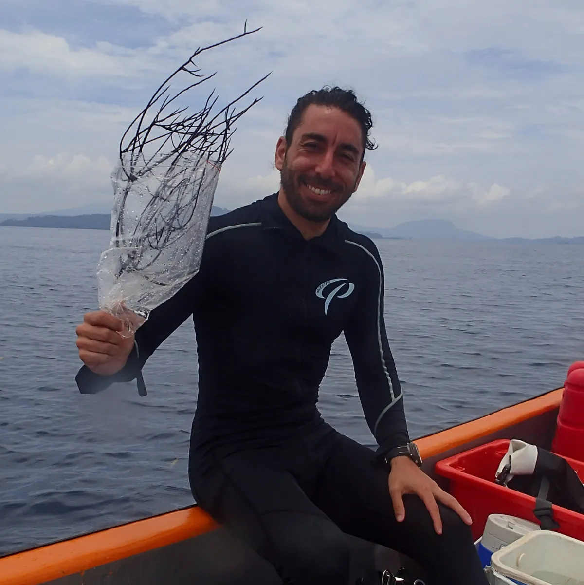 A man sitting on a boat and holding a black coral specimen