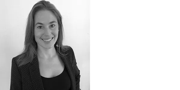 Black and white portrait of Jennifer Whitten, a light-skinned woman with shoulder-length light brown hair, who is wearing a dark jacket with small polka dots over a black top.