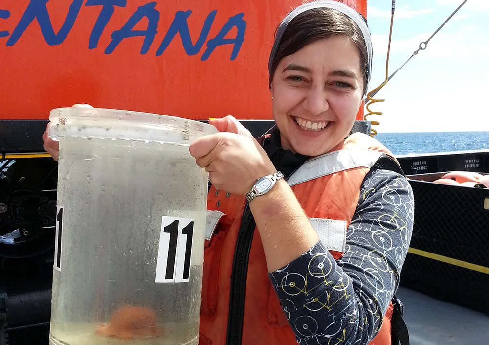 Stephanie Bush on a ship's deck holding a bucket with an orange octopod inside