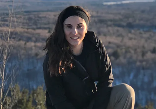 Kali DeMarco sitting with a field in the background.