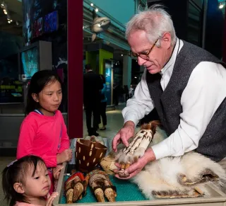 Archaeologist Stephen Loring in museum exhibit, showing children samples of fur