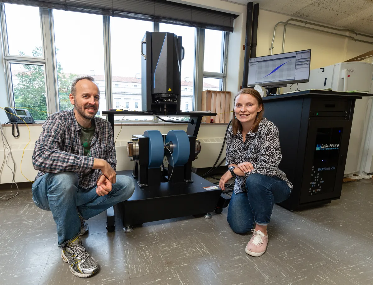 A light-skinned man and woman crouch next to a magentometer