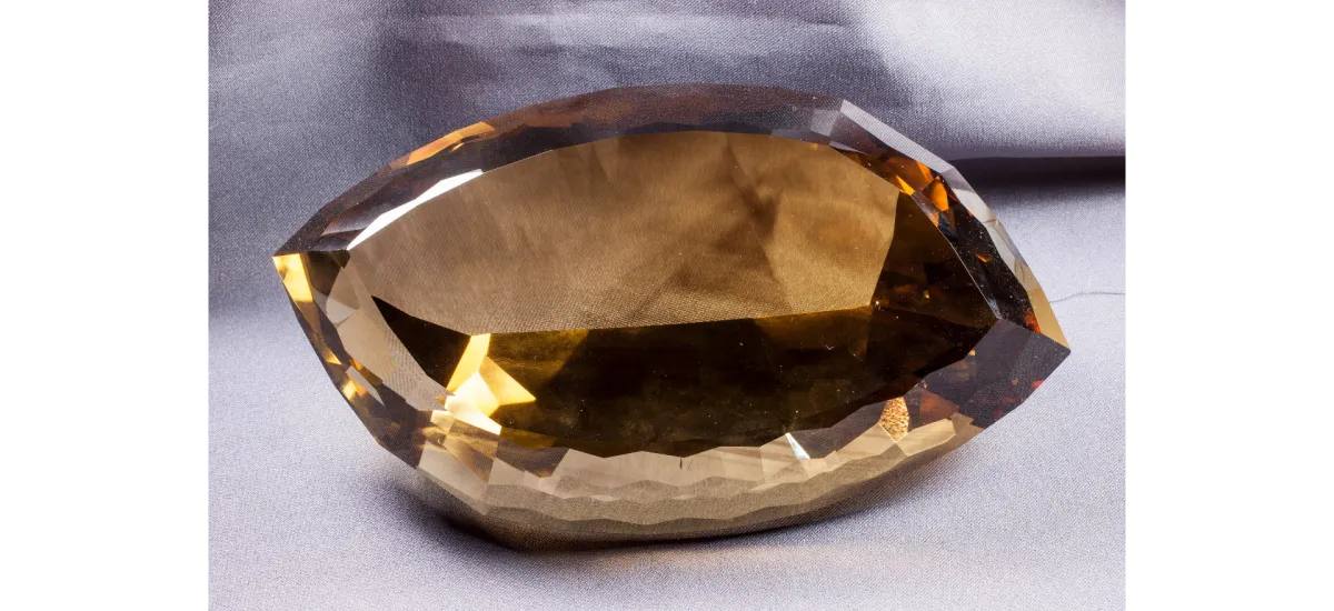 Large brown and yellow, faceted gem in the shape of an American football.