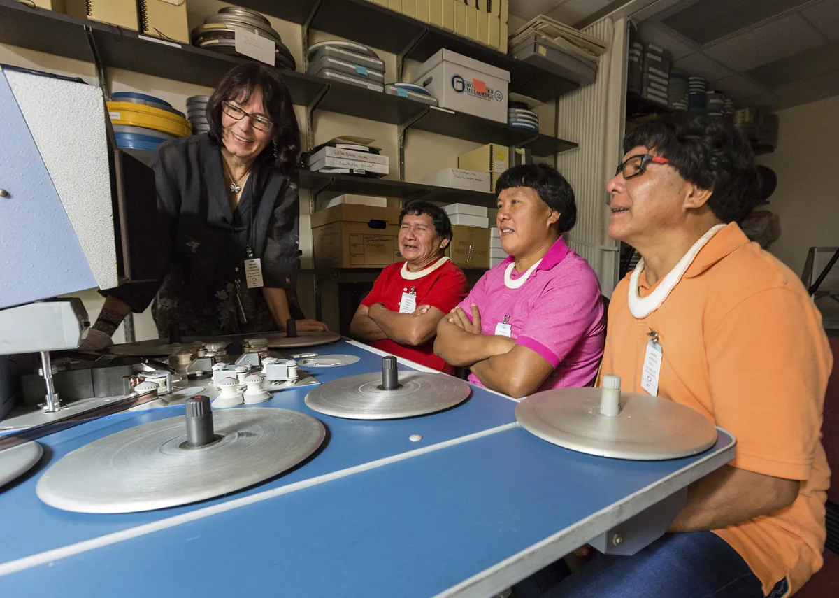 Three Wauja community researchers cheerfully watch historic film in the HSFA