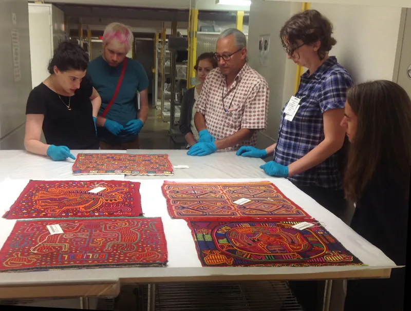 SIMA students and faculty examining molas, colorful shirt panels from Kuna people in Panama