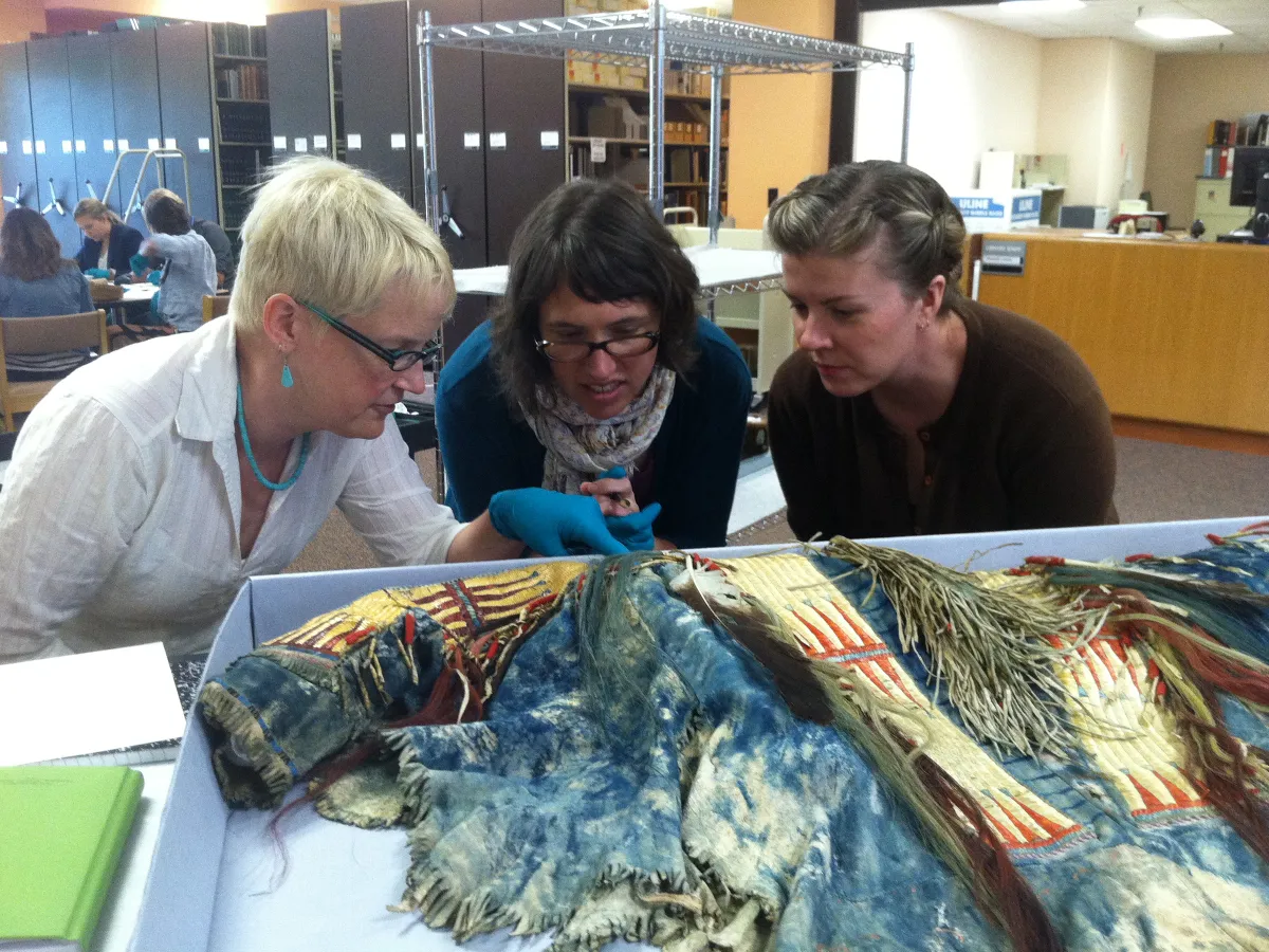 SIMA Students and faculty examining and discussing a Plains Indian shirt
