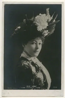 Black-and-white photo of a woman wearing an ornate hat with flowers